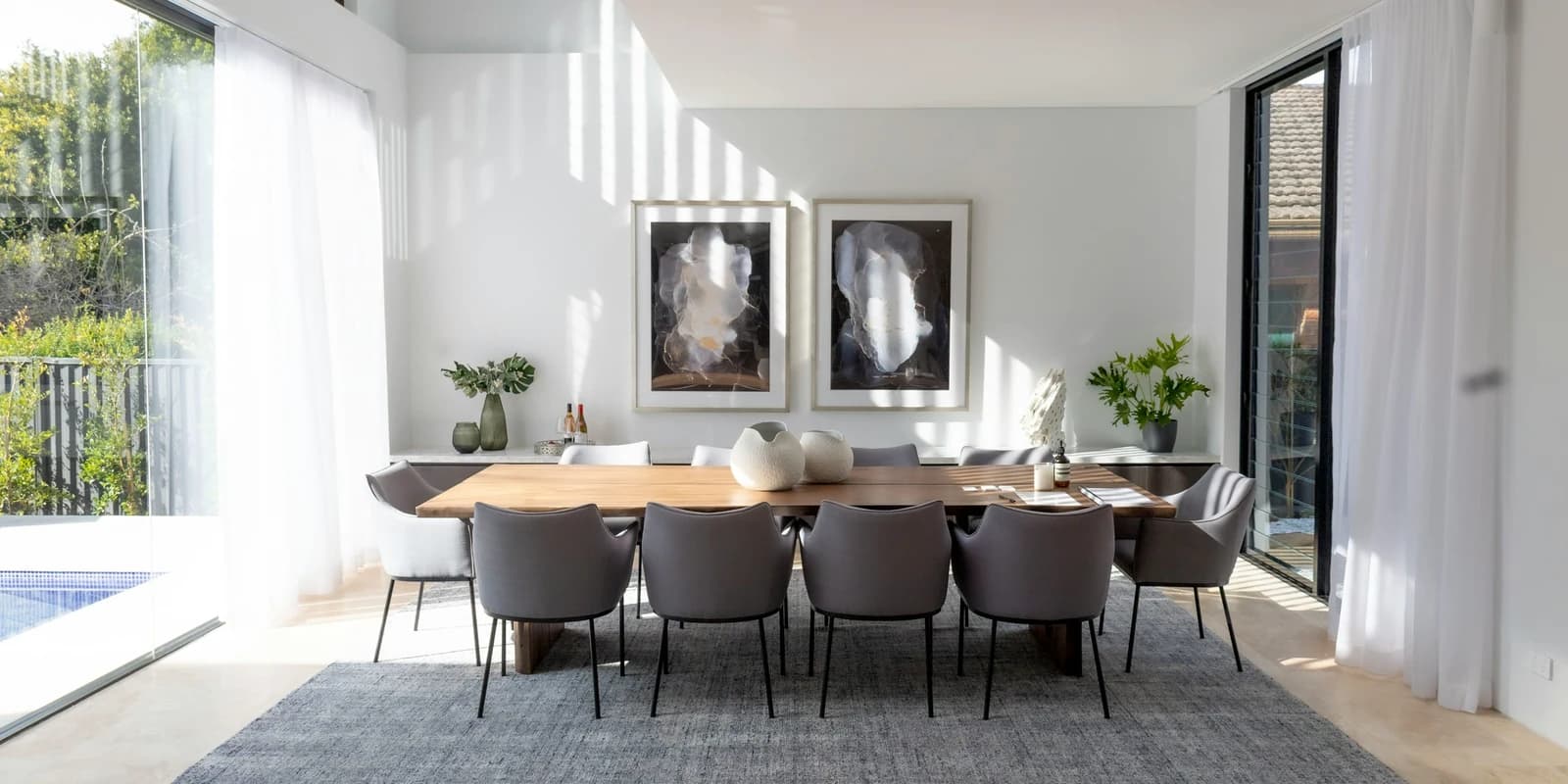 A bright modern dining room opening onto a terrace through full-height glass